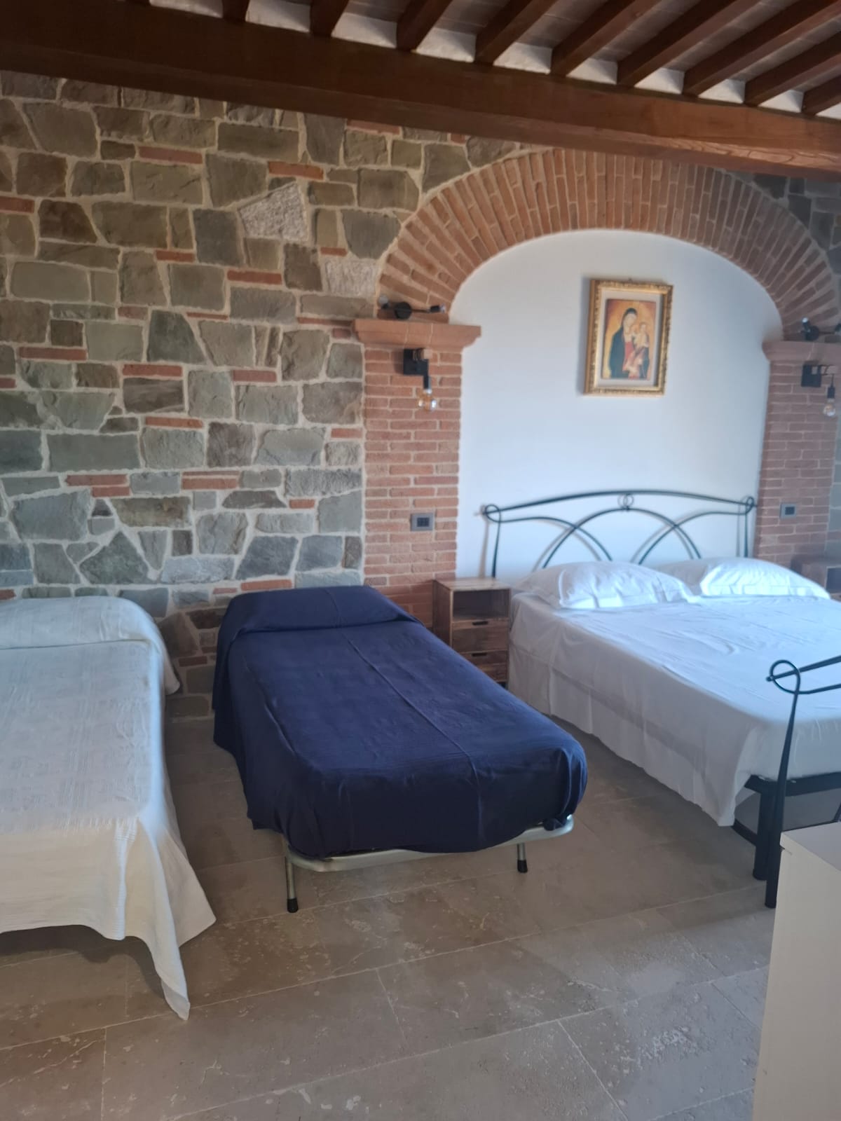 Camera spaziosa con letti e parete in pietra
